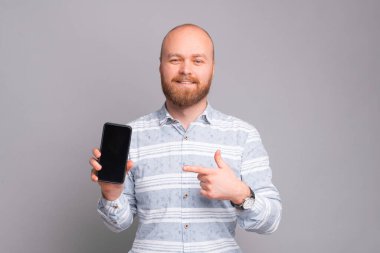 Neşeli adam telefon ekranına bakıyor ve gülümsüyor.