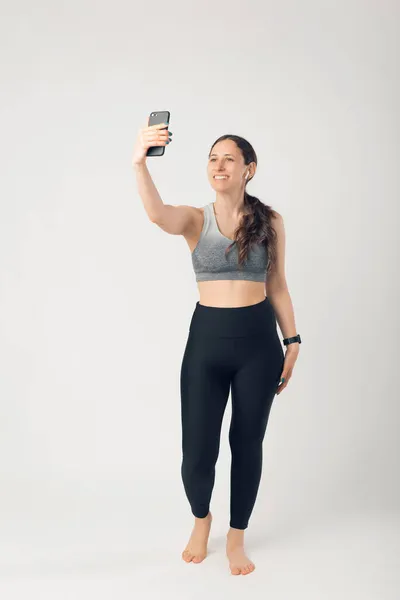 Foto de larga duración de la mujer del deporte tomando selfie sobre la pared blanca —  Fotos de Stock