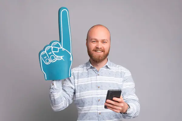 迷人的上班族手握风扇泡沫手套，手持灰色背景的智能手机 — 图库照片