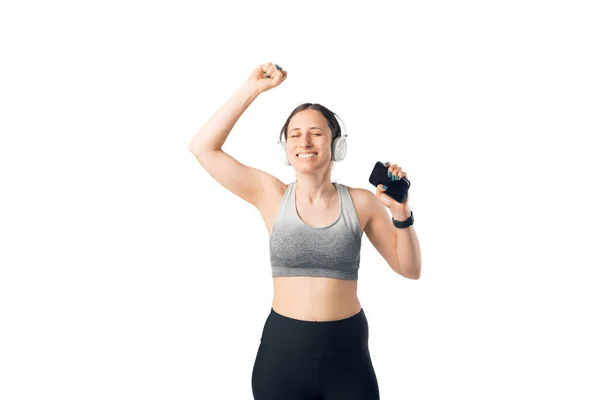 Portrait of pretty woman listening to music using wireless headphones in studio after workout — Stock Photo, Image