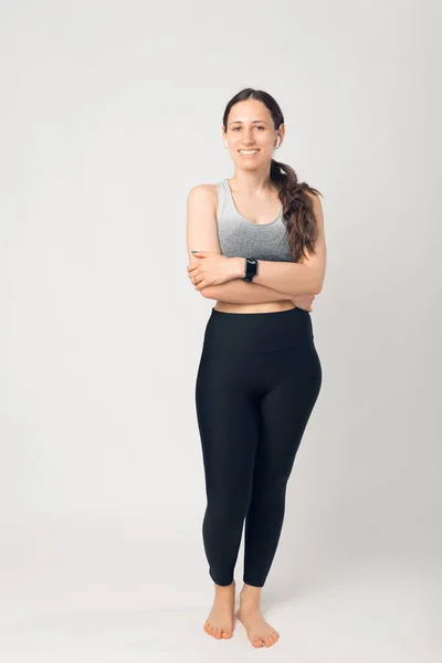 Photo pleine hauteur de jeune femme en forme, posant à l'appareil photo avec les mains pliées — Photo