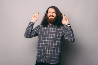 Yakışıklı sakallı adam gri arka planda şans diliyor.