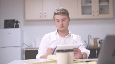 Bekar bir gencin ofis mutfağında oturup evraklarla çalıştığı görüntüler.