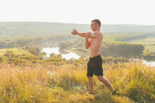 Photo of young sportsman warm up outdoors at sunset — Stock Photo, Image