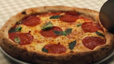 Lezzetli İtalyan pizzası, peyniri ve salamı keserken çekilen görüntüleri kapatın.