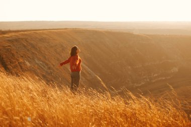 Güzel manzaralı bir tepede güneşlenen genç bir kadının fotoğrafı.