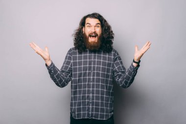 Gri arka planda el kol hareketi yapan sakallı genç adamın portresi, şok oldum.