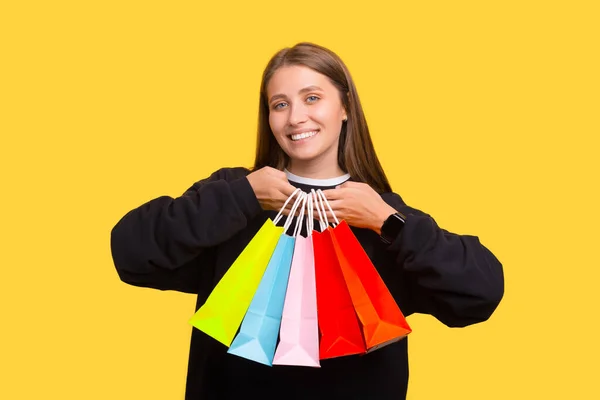 Молодая улыбающаяся женщина держит пять разноцветных пакетов для покупок. — стоковое фото