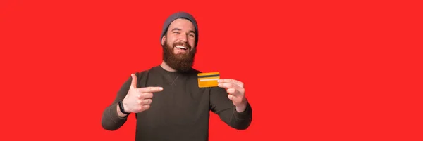 Banner formato foto di giovane uomo barbuto eccitato che punta alla carta di debito — Foto Stock