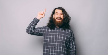 Gülümseyen, uzun saçlı ve sakallı neşeli genç bir adam.