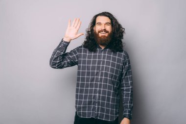 Kareli gömlekli genç sakallı adam gri arka planda 