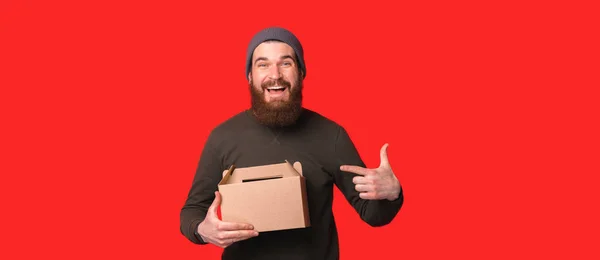 Niesamowity człowiek wskazujący na kartonowe pudełko w studio — Zdjęcie stockowe