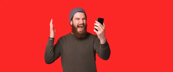 Podekscytowany mężczyzna krzyczy głośno podczas korzystania ze smartfona — Zdjęcie stockowe