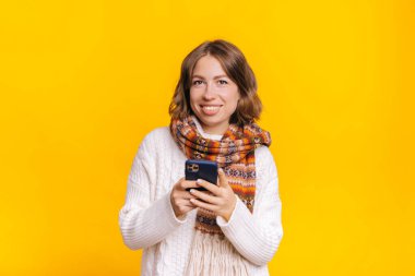 Stüdyoda akıllı telefonlara bakan neşeli bir kadın.