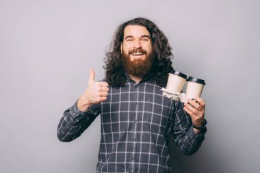 Kahveli olumlu adam baş parmağını gösteriyor.