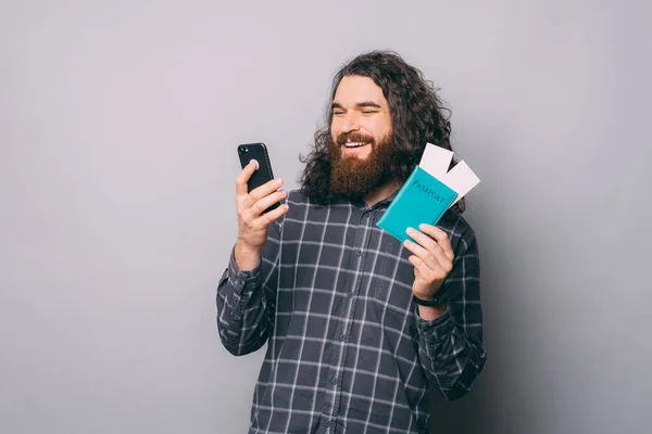 Cheerful man with tickets browsing smartphone — Stock Photo, Image