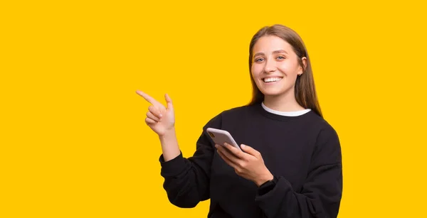 Shot of happy young woman enjoys mobile points away on free space for your advertising content — Stock Photo, Image