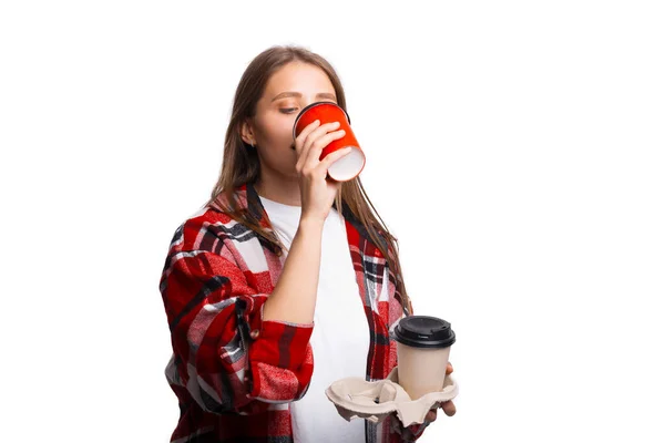 Young woman drinking cup of coffee, holding take away holder with cup, white background — Stock Photo, Image