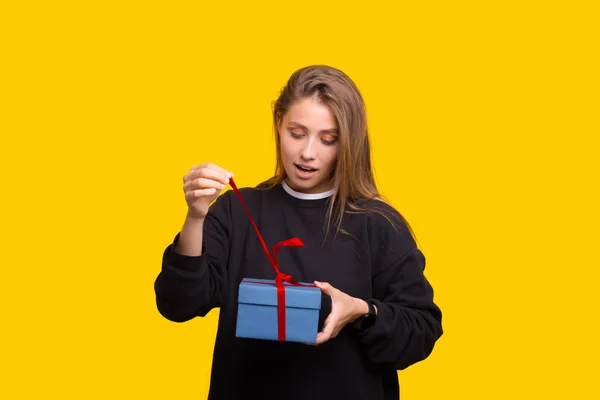 Porträt eines glücklich lächelnden Mädchens beim Öffnen einer Geschenkschachtel auf gelbem Hintergrund — Stockfoto