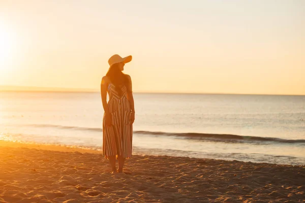 Фото женщины стоит на спокойном пляже заката — стоковое фото