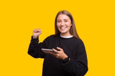 Genç kızın mutlu fotoğrafı zaferi kutluyor. Başarılı yumruklar cep telefonuyla oynuyor.