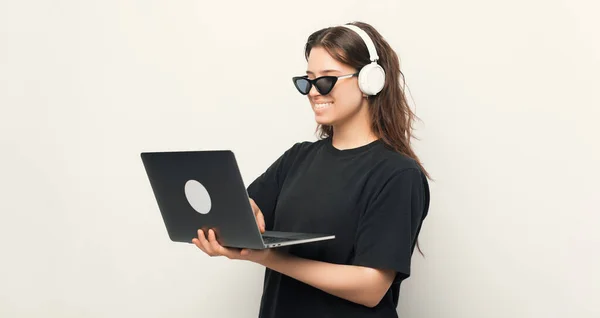 멋진 선글라스를 끼고 노트북 과 헤드폰을 사용하고 있는 행복 한 젊은 여성, 기술에 대한 배려 — 스톡 사진