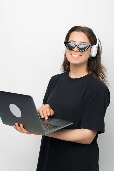 Ritratto di giovane donna in occhiali da sole cool che trasporta laptop e utilizza cuffie, concetto di gadget — Foto Stock