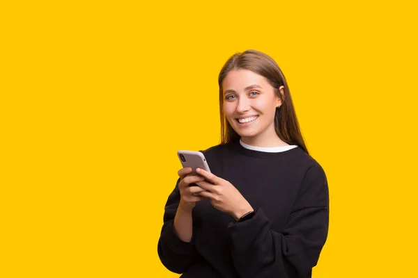 Foto de jovem sobre fundo amarelo enviando uma mensagem com o celular — Fotografia de Stock