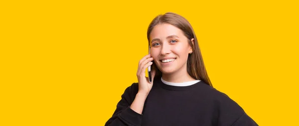 Joyeux jeune fille, parler avec des amis au téléphone sur fond jaune — Photo