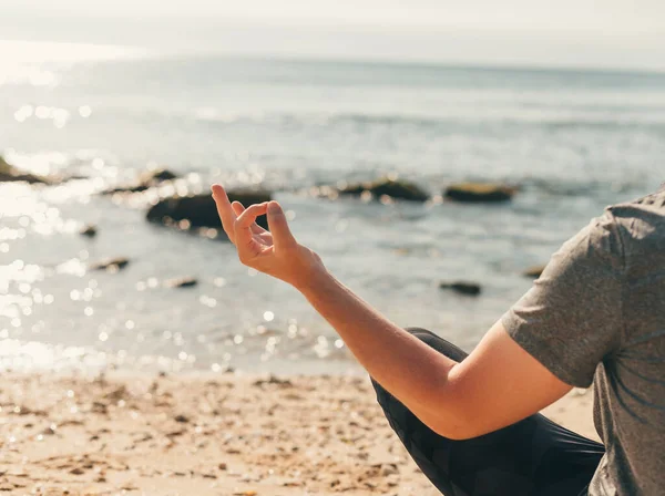 A fickó egy jóga szőnyegen ül a parton lótuszpózban és meditál. — Stock Fotó