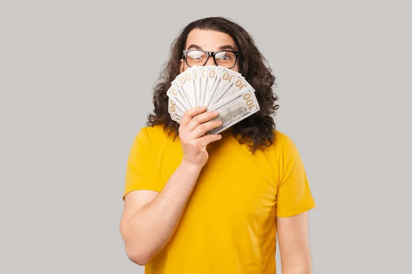 Foto de joven emocionado joven sosteniendo el dinero sobre la cara —  Fotos de Stock