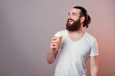 Neşeli, sakallı hippi bir fincan kahve içiyor ve gülümsüyor.