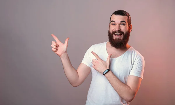 Hey schau dir dieses Angebot an, fröhlicher gutaussehender Mann mit Bart, der auf Copyspace zeigt — Stockfoto
