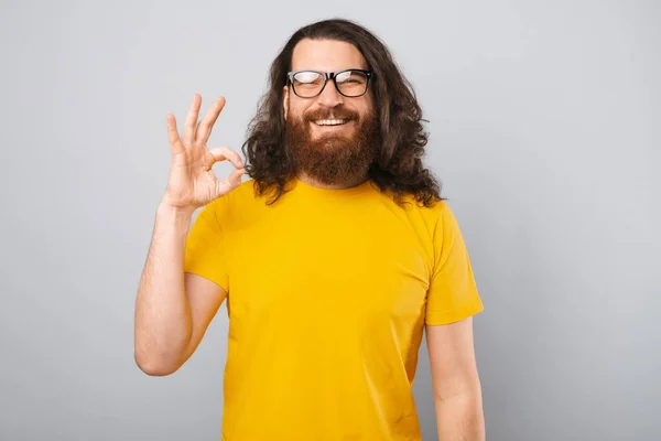 Portret van vrolijke jonge bebaarde man met lang haar met ok gebaar — Stockfoto