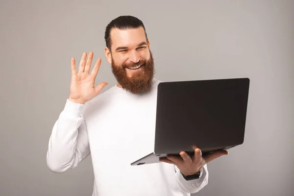 Barbudo hombre está hablando a través de la cámara de vídeo desde el ordenador portátil y decir hola. — Foto de Stock