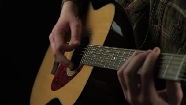 Primer vídeo del hombre tocando en la guitarra acústica sobre fondo oscuro — Vídeo de stock