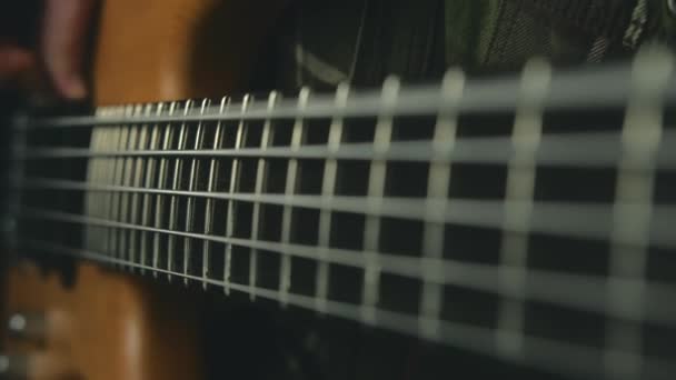 Nahaufnahme von Basssaiten in Zeitlupe vor dunklem Hintergrund, Mann spielt an der Bassgitarre — Stockvideo