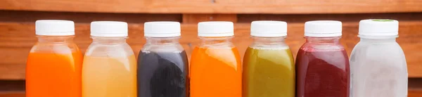 Many detox juice bottles on table over wooden background — Stock Photo, Image