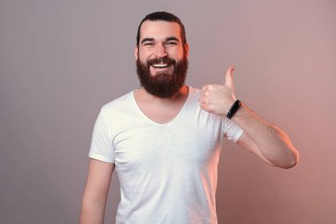 Yakışıklı sakallı adam gri arka planda jest yapıyor..