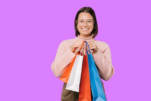 Молодая улыбающаяся женщина держит перед собой сумки с покупками.. — стоковое фото