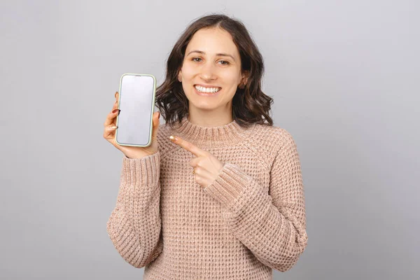 A széles mosolygó nő a telefonra mutat, amit tart.. — Stock Fotó