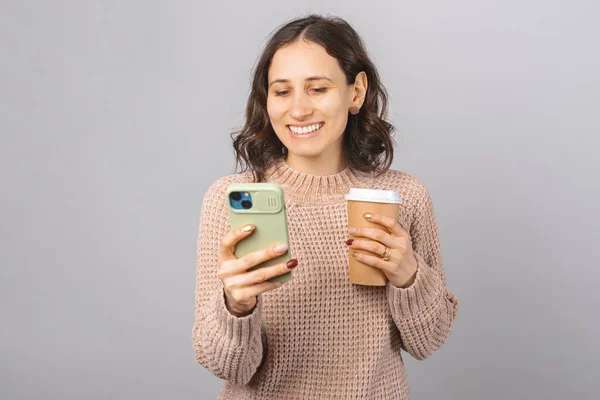 Pessoa feminina otimista está desfrutando de uma xícara de café enquanto navega ou envia mensagens de texto por telefone. — Fotografia de Stock