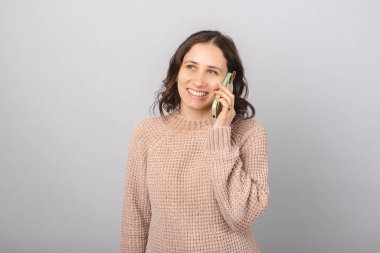 Gülümseyen kadın telefonla arıyor. Gri arkaplanda portre.