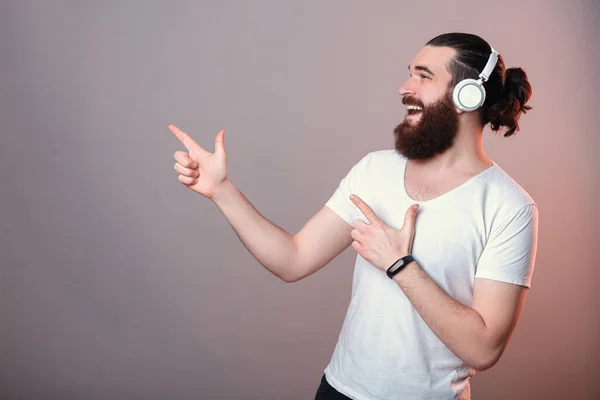 Estudio Hombre Barbudo Escuchando Música Los Auriculares Señalando Lado Con — Foto de Stock