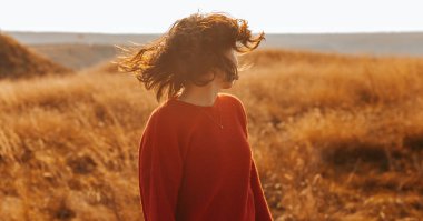 Gün batımında bir tepede dikilirken kafasını sallayan bir kadının yüzsüz portresi..