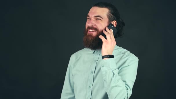 Zamknij wideo szczęśliwy młody człowiek mówi na smartfonie przez ciemne tło i uśmiech — Wideo stockowe