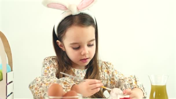 Närbild video av söt ung flicka målning påsk ägg i vitt — Stockvideo