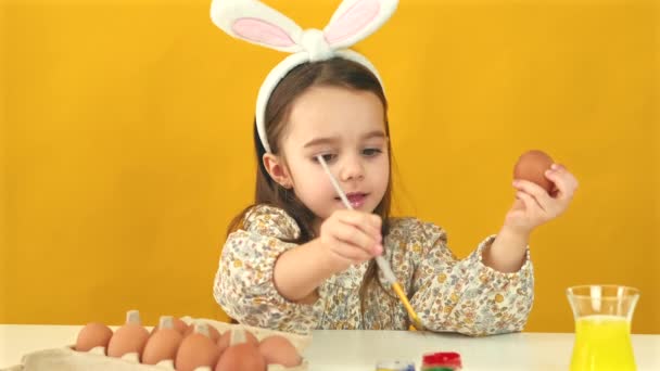 Filmato di bambina che dipinge uova di Pasqua su sfondo giallo — Video Stock