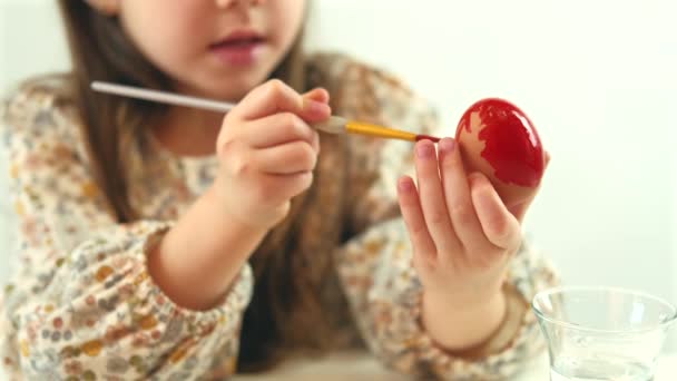 Gros plan vidéo de petite fille peignant Œuf de Pâques en rouge — Video