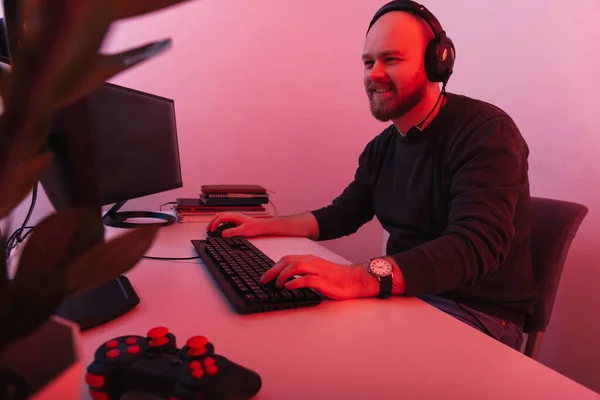 頭の電話をかけながら 若いはげ髭の男がコンピューターで働いているのを笑っている レッド ライト ショット — ストック写真